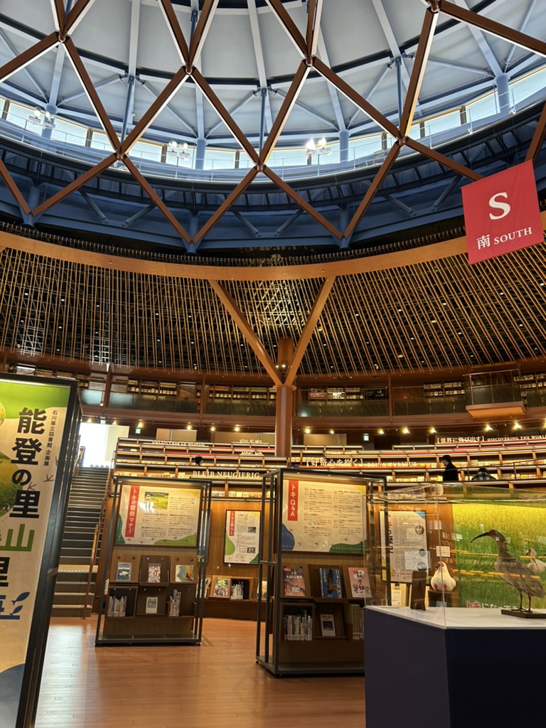 石川県立図書館の本棚と展示エリア。ドーム天井と能登の里山里海の展示